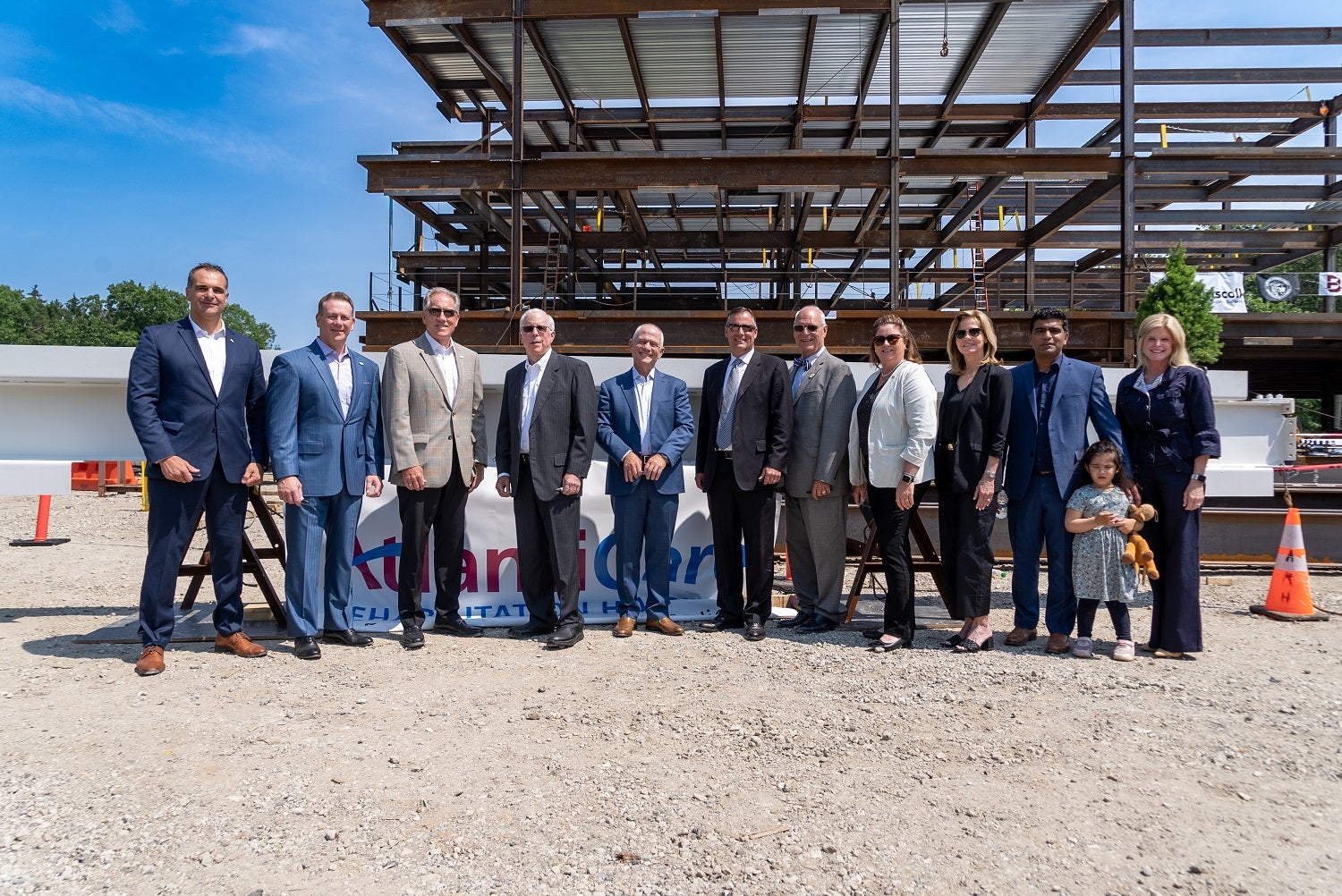 Leaders from AtlantiCare and Select Medical, along with elected officials, stand in front of the ceremonial white beam.