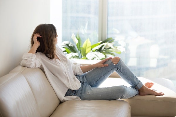 Woman sits on couch and looks out window