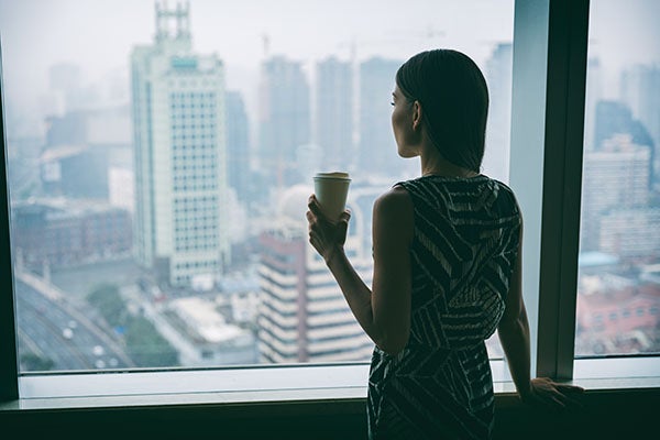 Woman with coffee cup looking over city skyline.